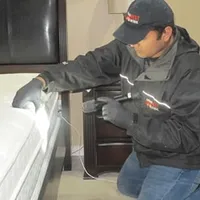 Bed bug inspection technician checking a mattress and bed frame for signs of infestation in Lakewood, CO
