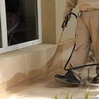 General pest control technician spraying exterior perimeter around a home in Lakewood, CO