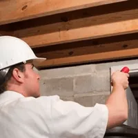 Termite inspection technician checking a basement wall and framing for termite activity in Lakewood, CO
